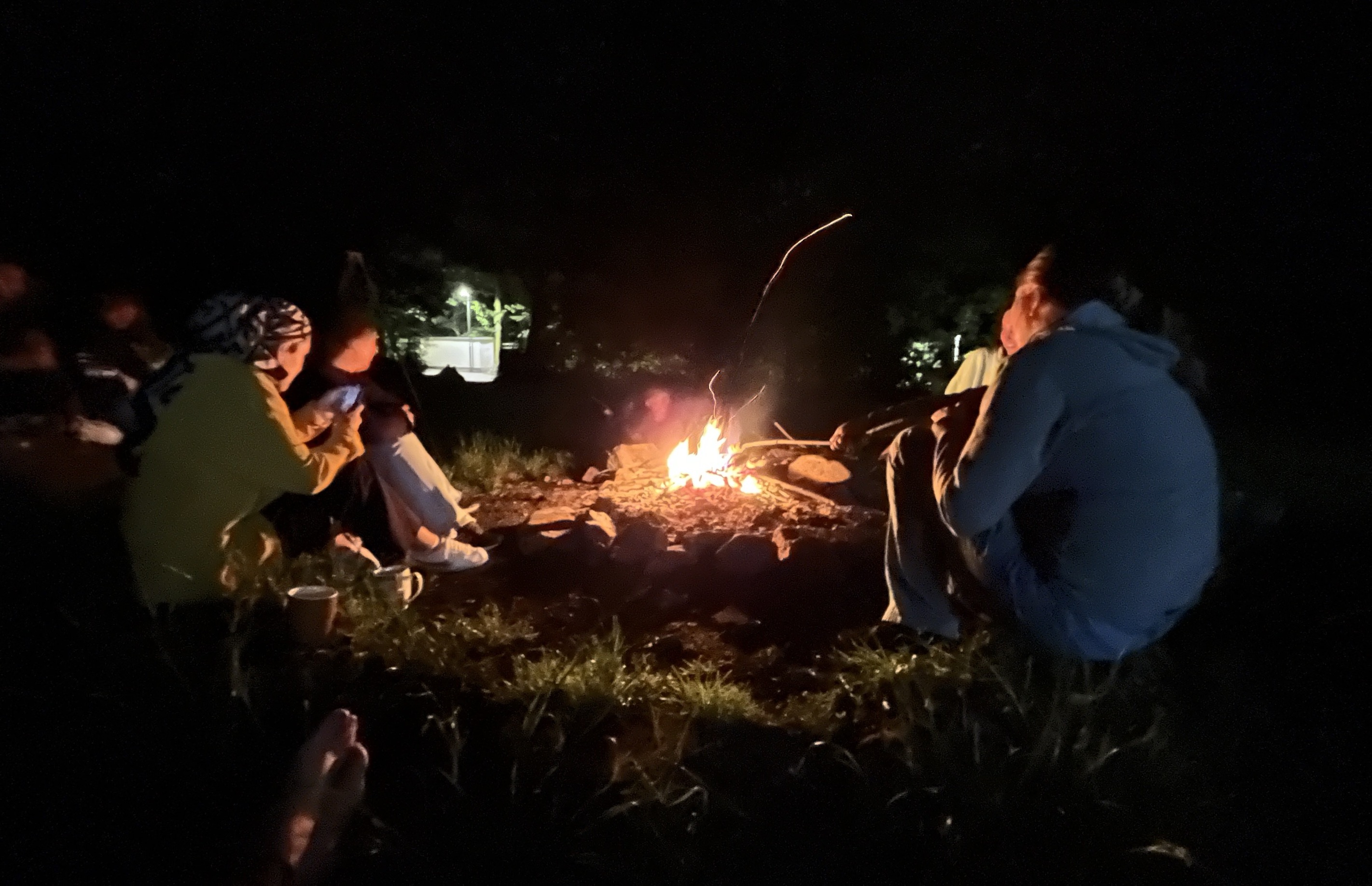 Menschen sitzen um ein Lagerfeuer im Dunkeln